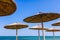 View on blue sea under thatched beach umbrella, wooden sunshade