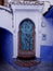 View of blue wooden door in blue and white alley, Chefchaouen, Morocco