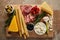 View of board with breadsticks, cheese, salami slices and antipasto ingredients on brown