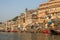 View from a boat glides through water on Ganges river along shore of Varanasi.