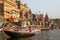 View from a boat glides through water on Ganges river along shore of Varanasi.