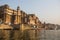 View from a boat glides through water on Ganges river along shore of Varanasi.