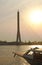 View of a boat in the river, the bridge tower and city on background under orange sky evening sunset, backlight photo