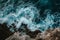 A View of a Body of Water From Above, Elevated view of ocean waves splashing against a rocky shoreline, AI Generated