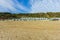 A view of the Boscombe Beach with sandy beach, colorful beach huts along the promenade with cliff under a beautiful blue sky and