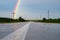 View from the bottom of the road is visible asphalt texture, the road after the rain poles along the road and part of the rainbow