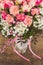 View of a bouquet of fresh pastel pink roses with a pink bow on rustic wooden background