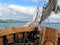 View from the bow of an old sailboat sailing in the Arctic sea with land in the background