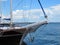 View of the bow of a yacht with a raised anchor in the seaport on a sunny day. A lighthouse, a bright blue sky and a blue sea are