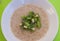 View of a bowl of porridge against green background with chopped kiwi fruit