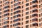 View of brick wall red contemporary apartment building with windows and balconies closeup