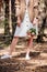 View of bride in brown jacket holding wedding bouquet in forest