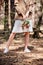 View of bride in brown jacket holding wedding bouquet in forest