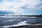 View of the bridge over the Volga, foaming water in the foreground with splashes in the distance and clouds