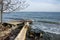 View of broken concrete pier in the sea, coastal destruction with single tree and blue sky