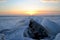 View of the broken melting ice cover of the Volga River against the backdrop of a magnificent sunset and clouds.