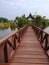 The view of brown wooden bridge at the lakeside garden