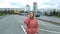 View from the building of a beautiful young girl with curly hair walks through a car parking in the city