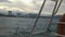 View of buildings and mountains from a moving ferry in the ocean.