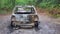 View burnt out and rusty car wreck alongside road and woods