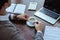 View of businessman with cup of coffee near laptop, calculator, papers and notebook at table