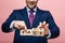 View of businessman holding wooden cubes with fake fact lettering on pink background