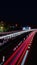 View of a bustling highway at night, illuminated by the red lights of vehicles and signs