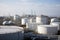 view of busy oil refinery, with huge storage tanks and pipes visible