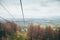 A view from a cablecar, cableway at mountains surrounded by forest going down to the meadow