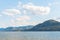 View of calm lake, forested mountains, and blue sky with clouds