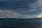 View of the calm undulating dark blue water of Lake Baikal, mountains on the horizon, sunset clouds