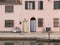 View of the canal of Comacchio. Reflection in the water. Two entrance doors with blue, yellow and white striped curtains. Two bic