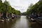 View of canal, parked boats, cars, trees and historical, traditional buildings