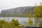 View from the car window of sad, harsh, dramatic landscape with a lake, river or fjord, a rock in the distance on the horizon and