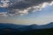 View of the Carpathian Mountains from the top of Goverla Mountain. The rays of the sun pierce through the overhanging clouds.