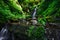View on cascade of waterfall hidden in green summer forest