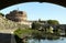 View of Castel Sant`Angelo from a bank of the Tiber river, framed by the shadow of a bridge