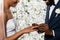 View of cheerful african american man putting wedding ring on finger of bride near flowers