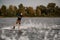 View of cheerful athletic guy riding wakeboard down the river on summer day.