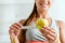 View of cheerful young woman measuring green apple