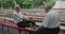 View of chess game between elder, thoughtful men having relax on outdoors bench