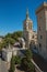 View of church with steeple tower next to the Palace of the Popes of Avignon.