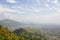 A view of the city in a green mountain valley in the mist under the blue sky and white clouds