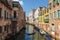 View of cityscape with colorful buildings on the banks of the canal and gondola with tourists, Venice