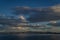 View of clear calm undulating blue water of Lake Baikal, mountains on the horizon, evening, sunset clouds