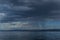 view of the clear calm undulating blue water of Lake Baikal, mountains on the horizon, rain clouds