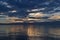 View of the clear calm undulating blue water of Lake Baikal, mountains on the horizon, sunset sky, clouds,