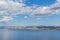 View of the clear calm undulating blue water of Lake Baikal, mountains on horizon, white clouds, blue sky
