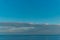 View of the clear calm undulating water of Lake Baikal, sunset clouds on the horizon, blue sky