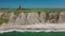 View of the cliffs at the danish coast with the red lighthouse Bovbjerg Fyr. Panoramic aerial view of beautiful nature landscape D